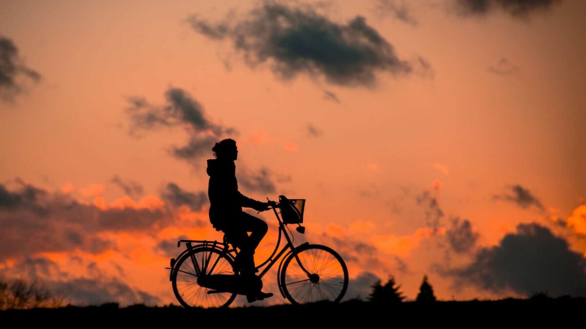 silhouette of person riding a bike during sunset